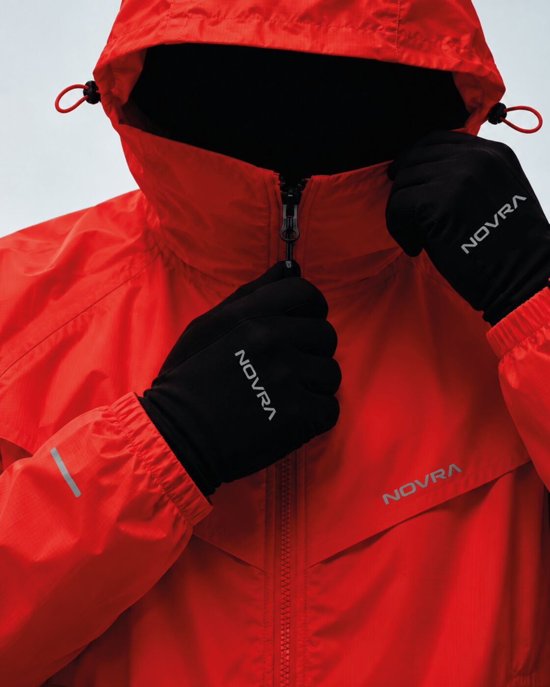 Veste technique NOVRA rouge à capuche, portée avec gants